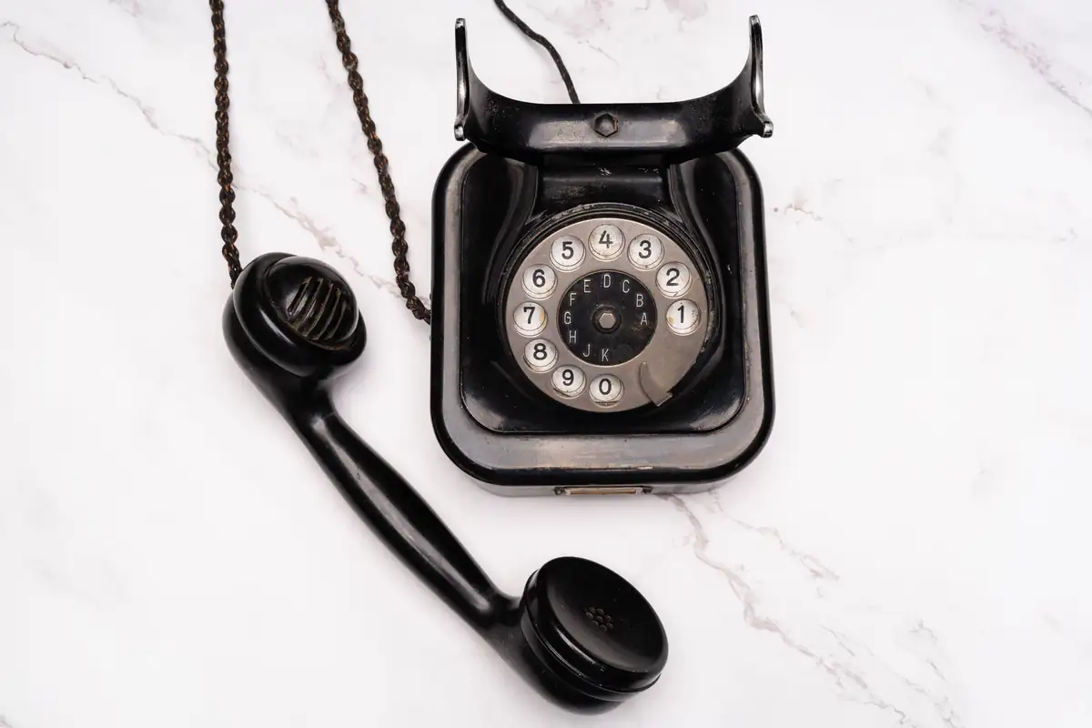 Combiné noir décroché posé à côté de son téléphone à cadran