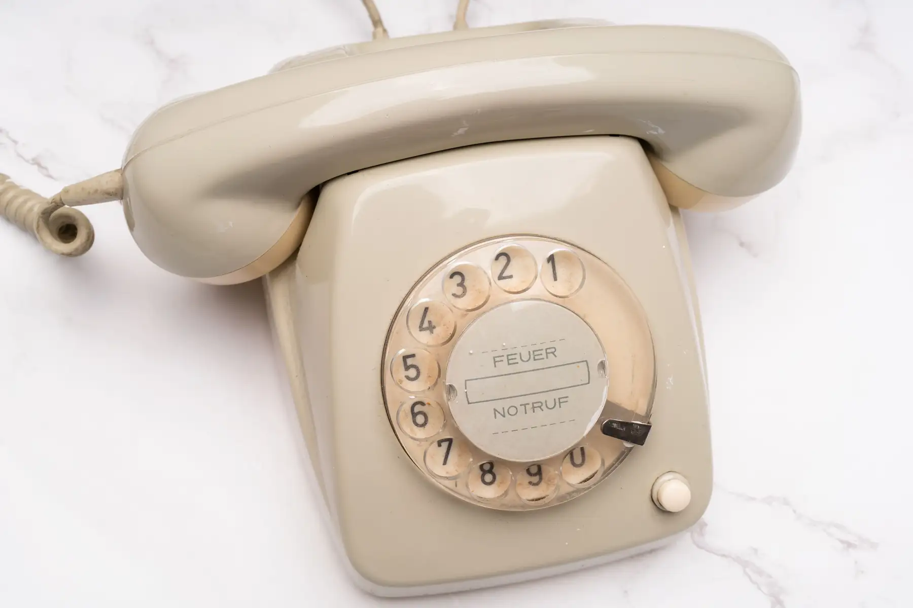 Téléphone vintage ivoire à cadran posé sur un plateau de marbre, livre d’or audio pour mariage