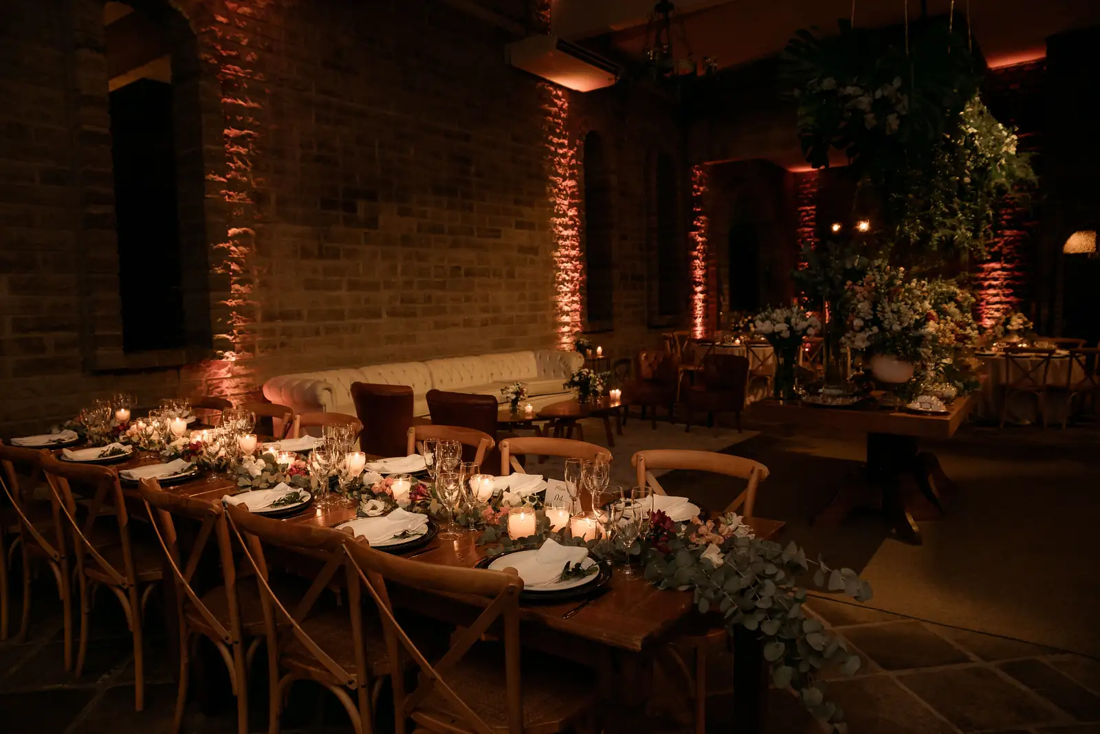 Longue table de réception dressée aux bougies dans une salle de mariage